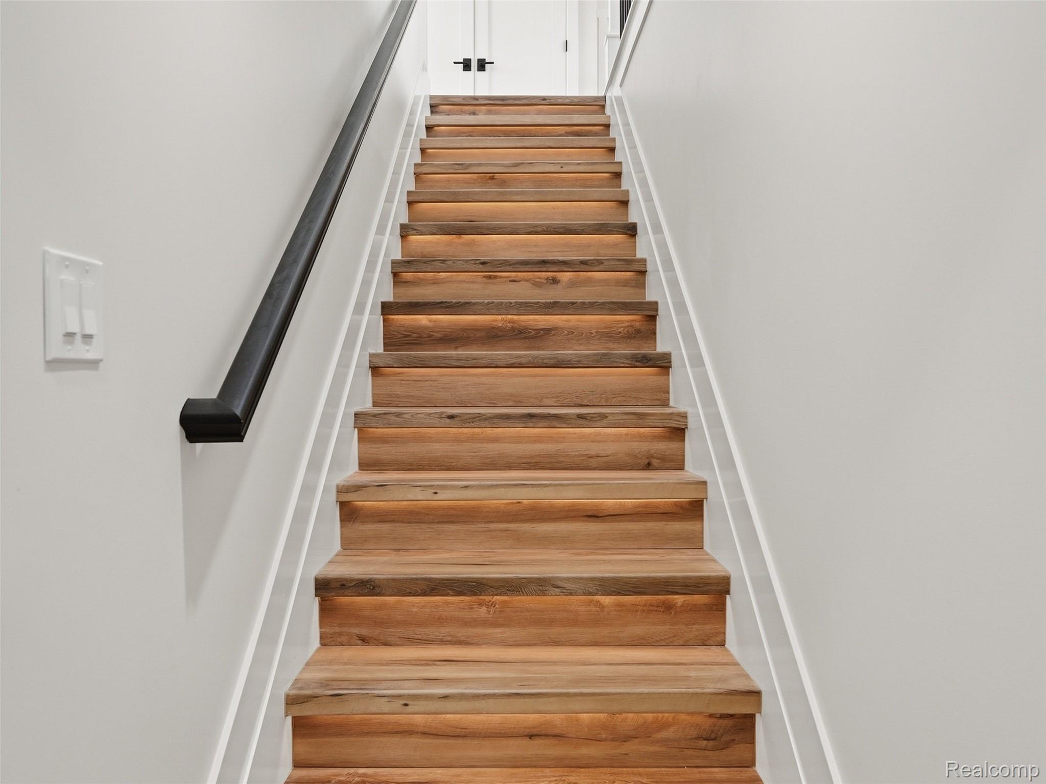 77850 Angling Road Richmond, MI 48062 - Photo 43 of 54 Wood-finish staircase featuring individual step lighting, a black handrail, and white risers