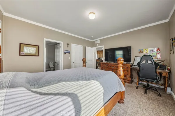 a bedroom with a bed a chair and a flat screen tv