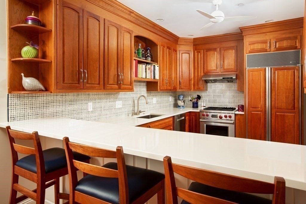 287 Langley Road, Unit 27 Newton, MA 02459 - Photo 5 of 17 a kitchen with stainless steel appliances wooden cabinets a stove a sink and a microwave