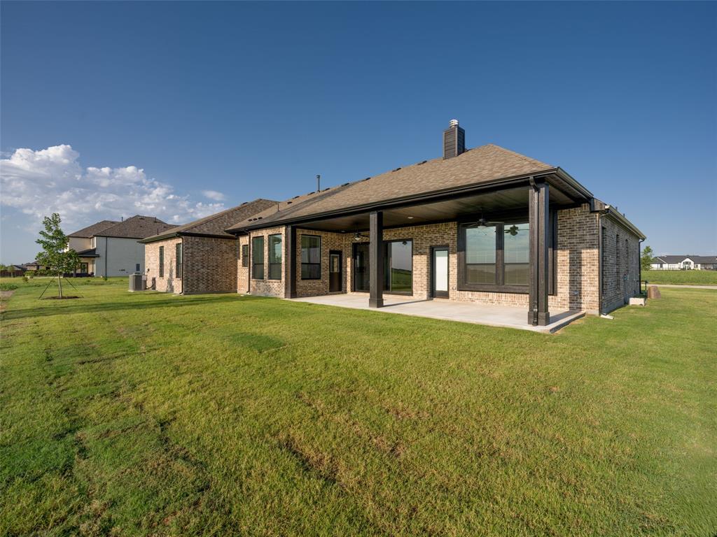 2108 Charters Circle Nevada, TX 75173 - Photo 33 of 37 Rear view of property with a patio, brick siding, a lawn, and a chimney