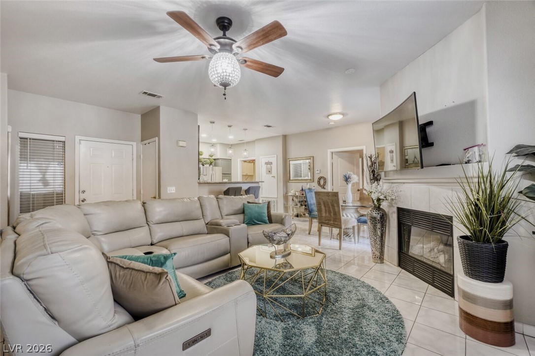 Living area featuring ceiling fan, light tile patterned floors, and a tile fireplace