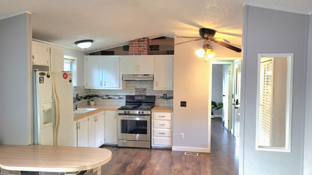 1525 South 400 East, Unit 63 Springville, UT 84663 - Photo 7 of 36 Kitchen with white refrigerator with ice dispenser, gas stove, white cabinets, dark wood-type flooring, and decorative backsplash