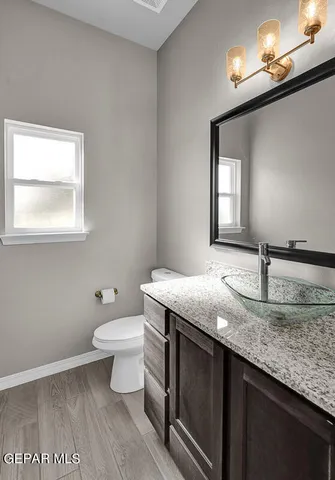 a bathroom with a granite countertop sink a toilet and mirror