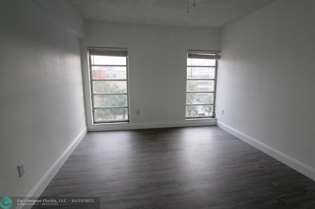 9159 Southwest 77th Avenue, Unit 411 Miami, FL 33156 - Photo 15 of 18 an empty room with wooden floor and windows