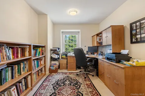 a view of a workspace with bookshelf and a window