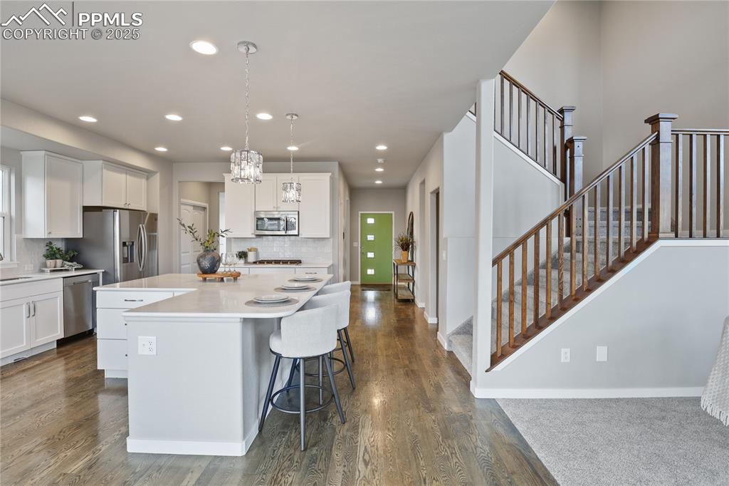 11848 Alydar Loop Colorado Springs, CO 80921 - Photo 11 of 50 Kitchen featuring stainless steel appliances, white cabinetry, decorative backsplash, dark wood finished floors, and recessed lighting