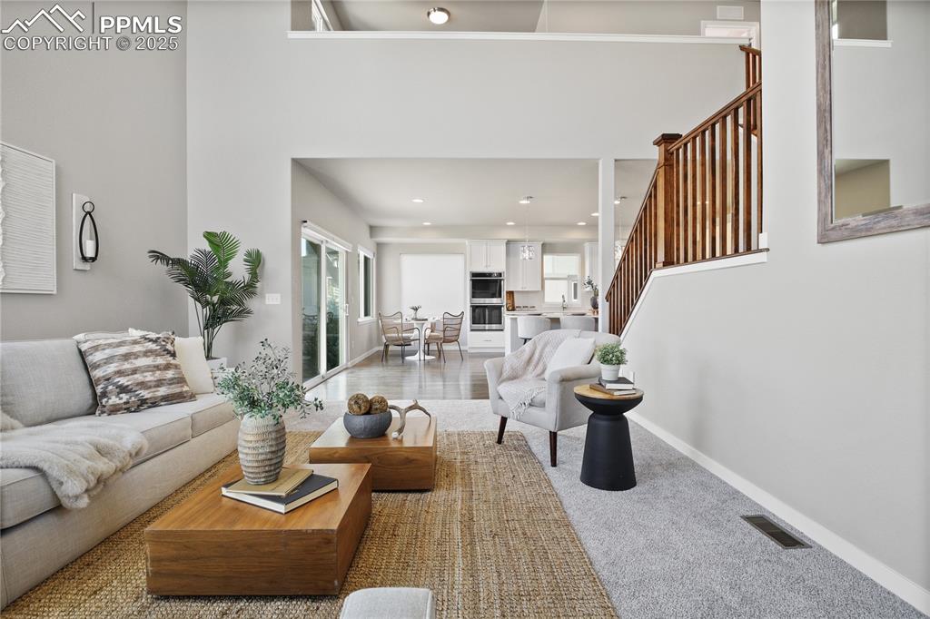 11848 Alydar Loop Colorado Springs, CO 80921 - Photo 16 of 50 Living room featuring stairs, baseboards, recessed lighting, a high ceiling, and light colored carpet