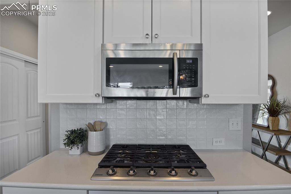 11848 Alydar Loop Colorado Springs, CO 80921 - Photo 19 of 50 Kitchen with appliances with stainless steel finishes, light countertops, and white cabinetry
