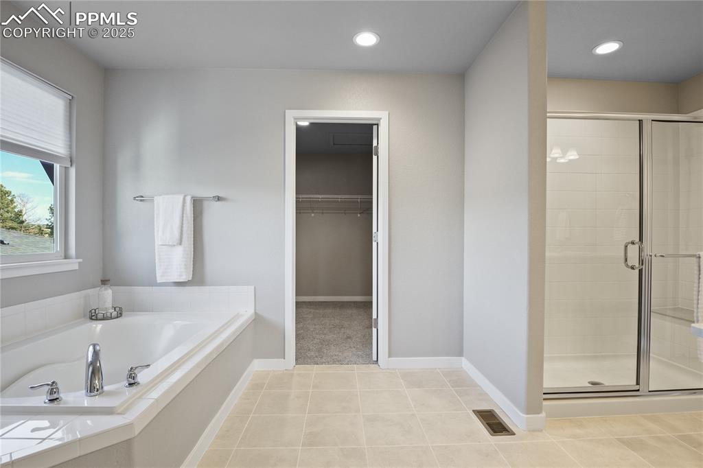 11848 Alydar Loop Colorado Springs, CO 80921 - Photo 31 of 50 Bathroom with a stall shower, a garden tub, a walk in closet, tile patterned floors, and recessed lighting