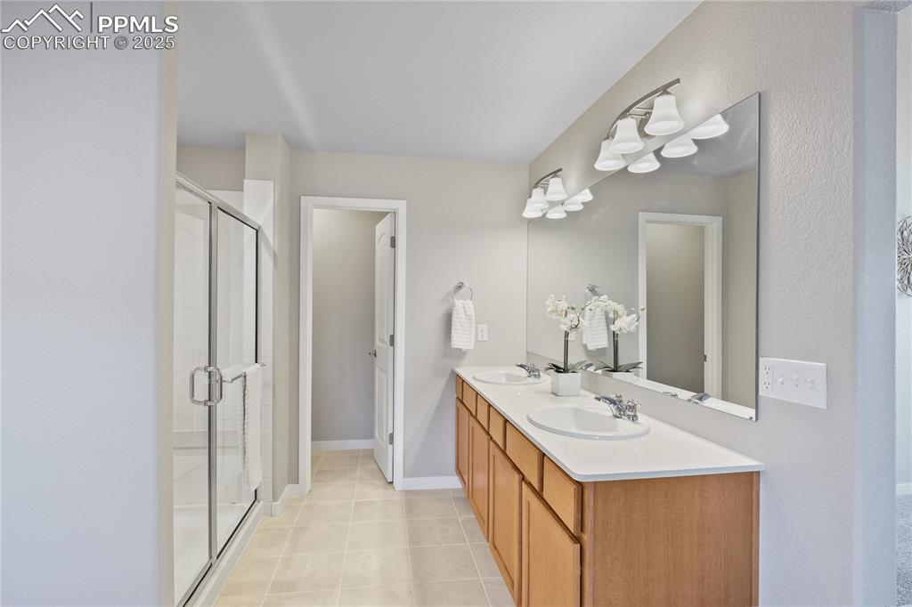 11848 Alydar Loop Colorado Springs, CO 80921 - Photo 32 of 50 Bathroom with a stall shower, tile patterned floors, double vanity, and baseboards