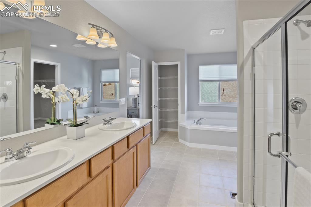 11848 Alydar Loop Colorado Springs, CO 80921 - Photo 34 of 50 Full bathroom featuring a shower stall, a spacious closet, a bath, tile patterned flooring, and double vanity