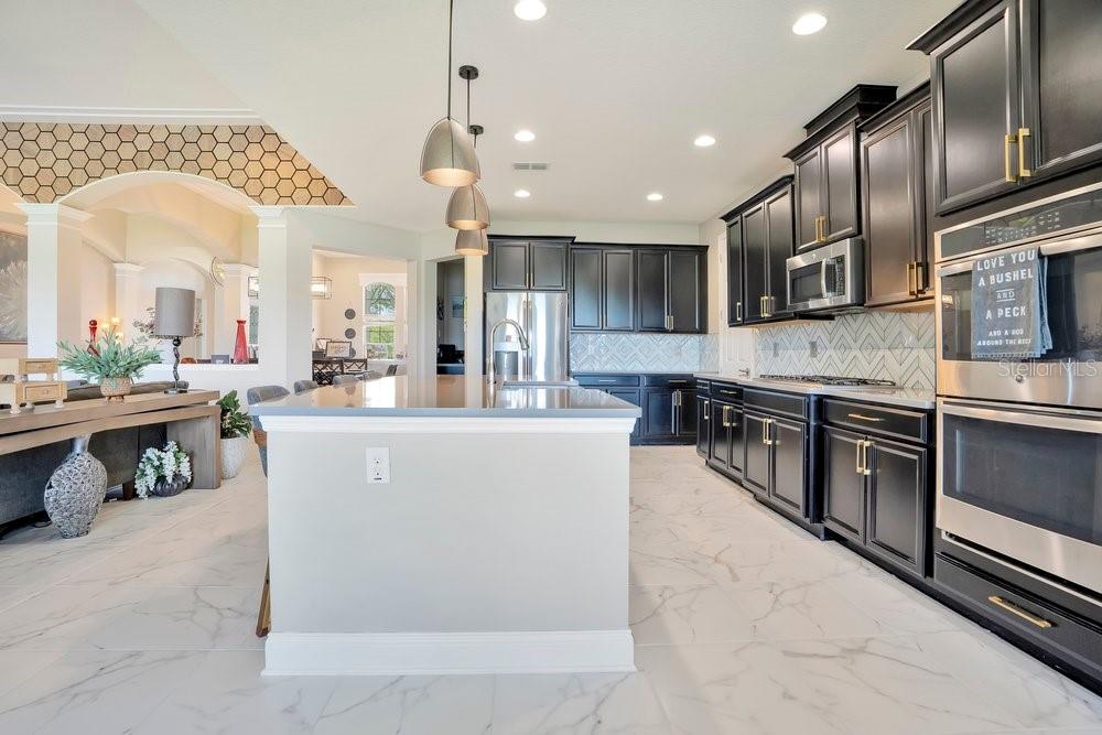 805 Riviera Bella Drive DeBary, FL 32713 - Photo 24 of 86 a large kitchen with stainless steel appliances kitchen island granite countertop a stove a sink dishwasher and a fireplace with wooden floor