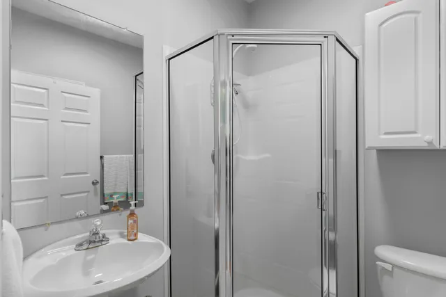 a bathroom with a sink a mirror a toilet and shower