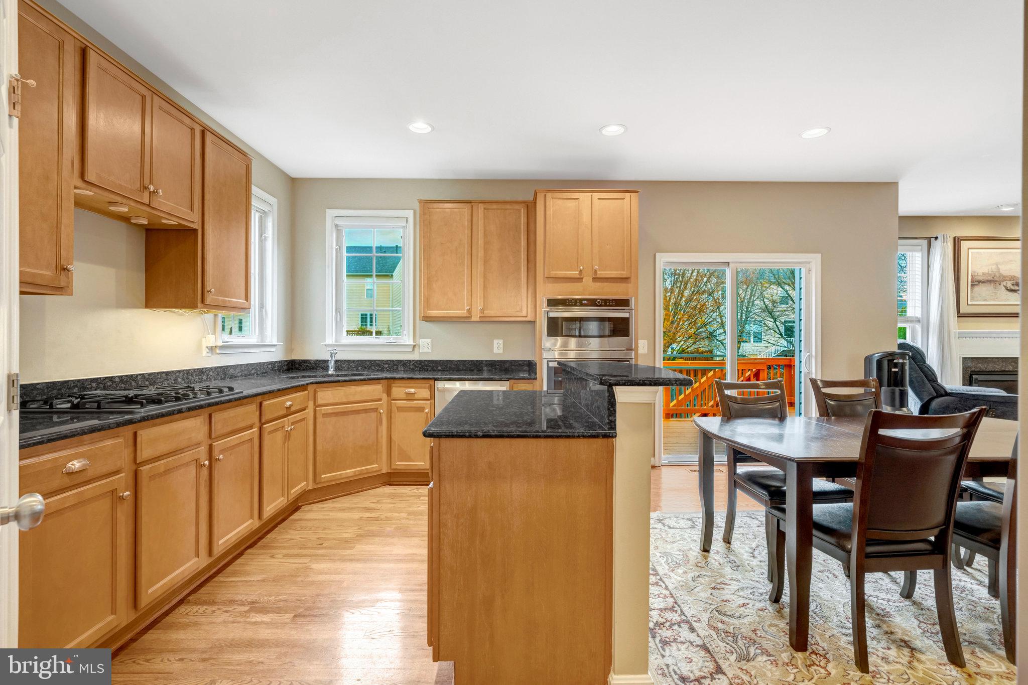 7726 Yalta Way Gainesville, VA 20155 - Photo 2 of 75 a kitchen with stainless steel appliances granite countertop wooden floor a stove top oven a sink a dining table and chairs