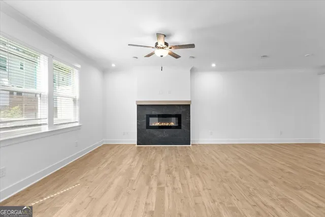 a view of empty room with wooden floor and fan