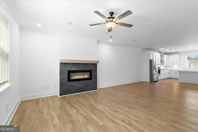 an empty room with a fireplace and kitchen view