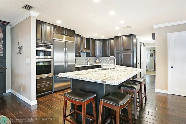 a kitchen with granite countertop stainless steel appliances a sink and a refrigerator