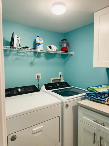 a view of a white house with a big yard and potted plants