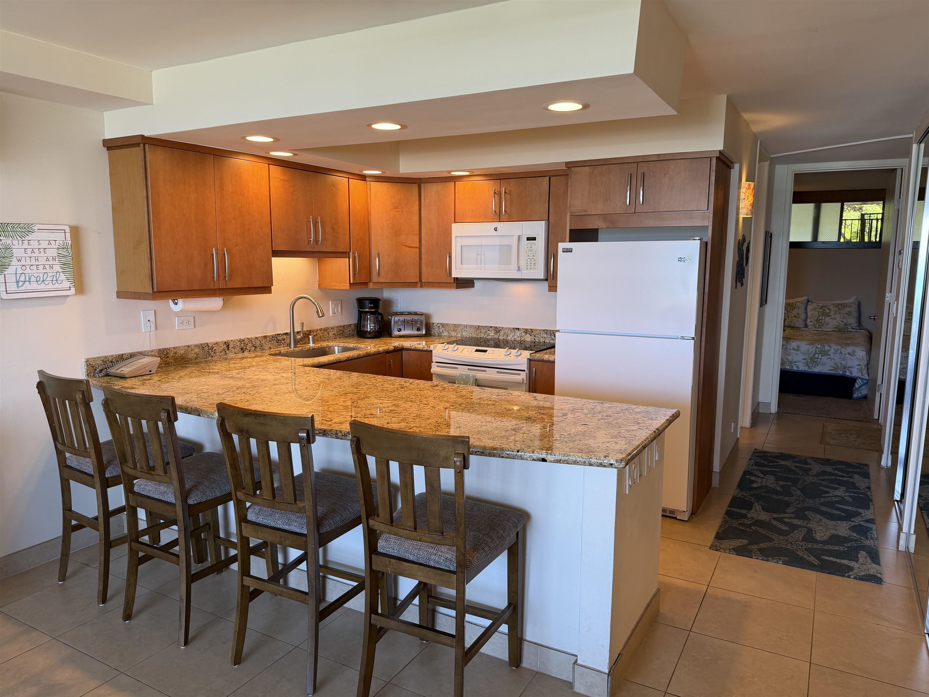 3543 Lower Honoapiilani Road, Unit L202 Lahaina, HI 96761 - Photo 2 of 22 a kitchen with stainless steel appliances granite countertop a table chairs sink and cabinets