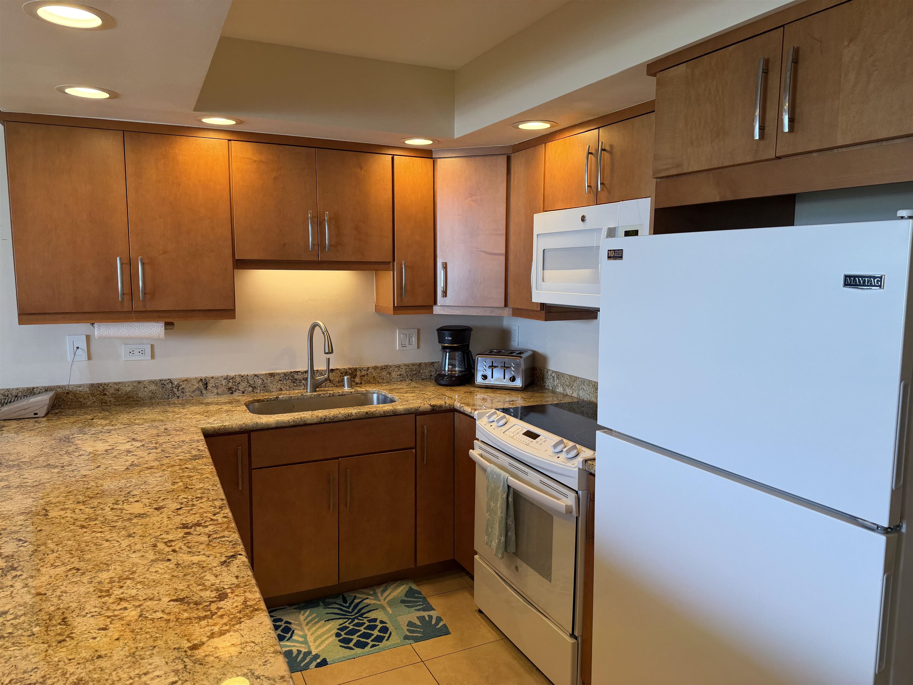 3543 Lower Honoapiilani Road, Unit L202 Lahaina, HI 96761 - Photo 5 of 22 a kitchen with stainless steel appliances granite countertop a refrigerator a sink dishwasher a stove top oven a dining table and chairs with wooden floor