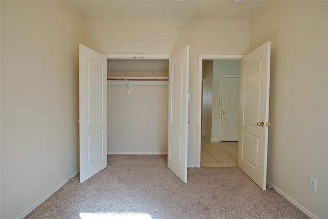 a view of an empty room with closet and a window