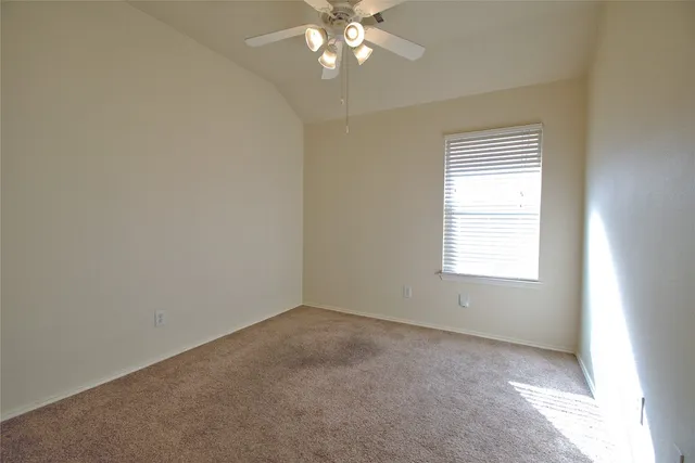 an empty room with a chandelier fan and windows