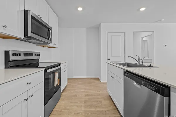 a kitchen with stainless steel appliances a sink dishwasher stove top oven and cabinets with wooden floor