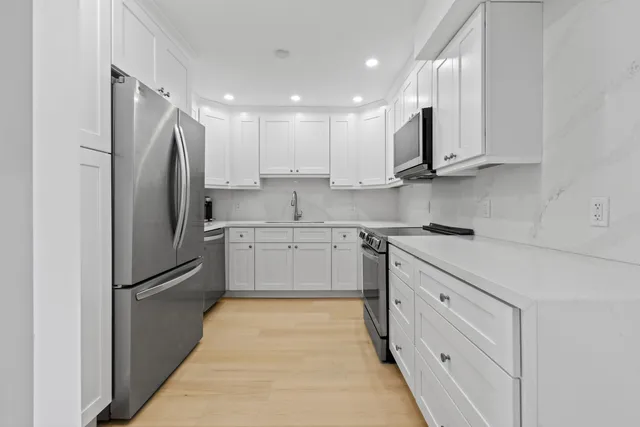 a kitchen with stainless steel appliances granite countertop a refrigerator sink and white cabinets