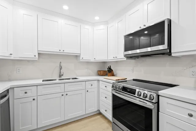 a kitchen with stainless steel appliances granite countertop grey cabinets a stove a sink and dishwasher