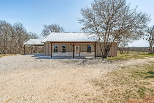 a backyard of a house with large trees and barbeque oven
