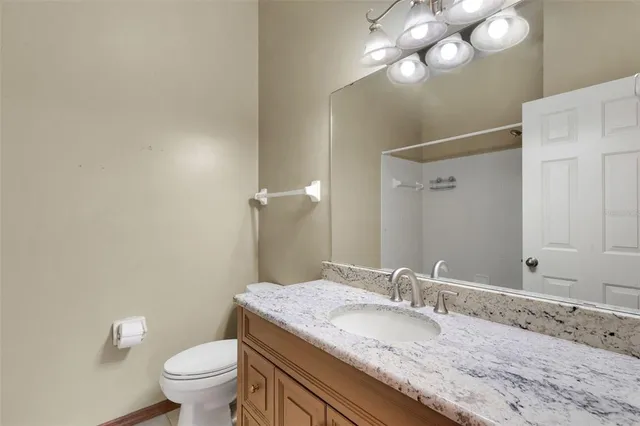 a bathroom with a granite countertop sink a toilet and a mirror