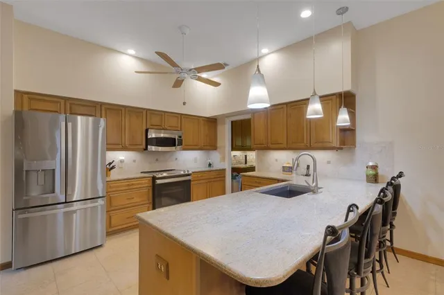 a kitchen with stainless steel appliances granite countertop a sink a stove a refrigerator with a dining table and chairs