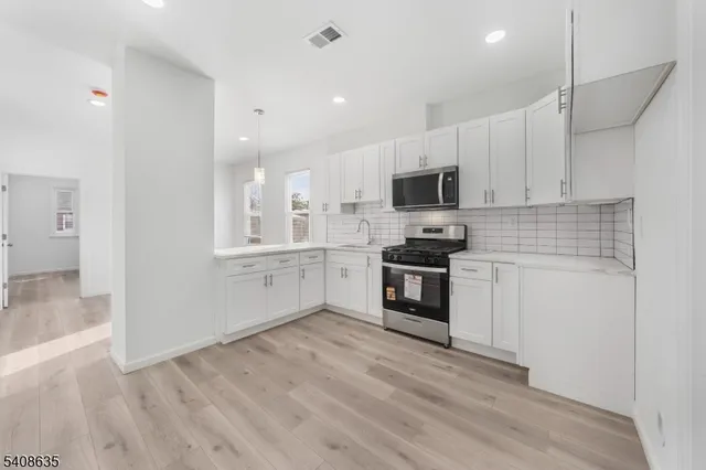 a kitchen with granite countertop white cabinets and stainless steel appliances