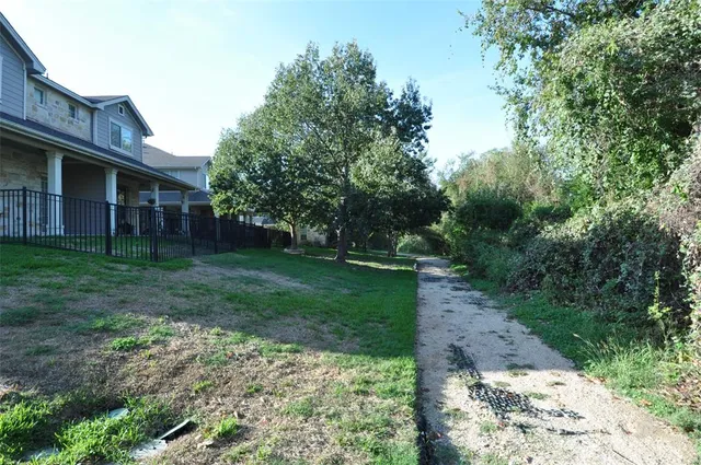a backyard of a house with plants and large trees