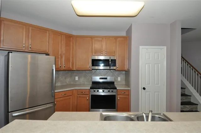 a kitchen with stainless steel appliances granite countertop a refrigerator and a stove top oven