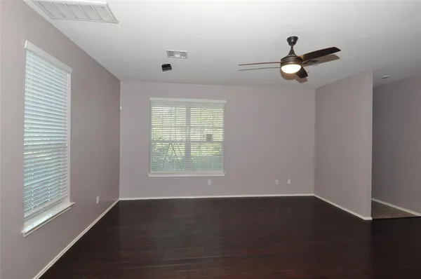 an empty room with wooden floor and windows