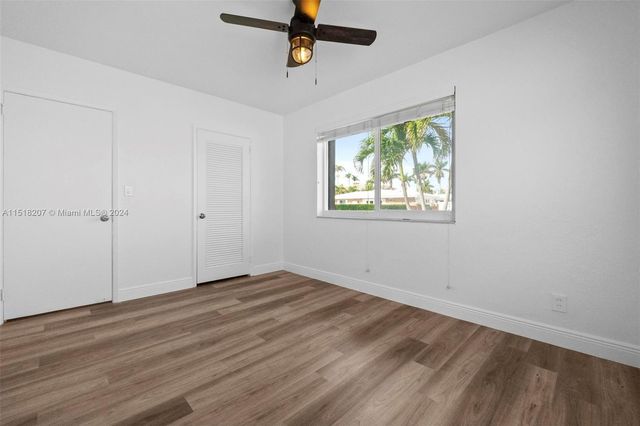 a view of an empty room with wooden floor and a ceiling fan