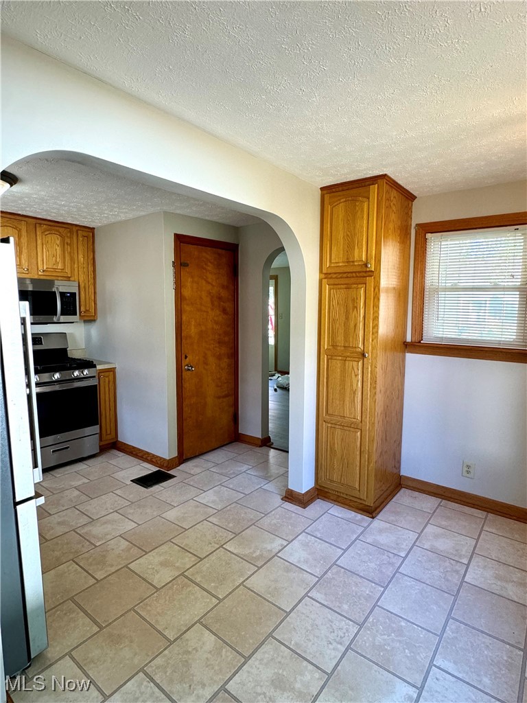 Kitchen with a textured ceiling and appliances with stainless steel finishes