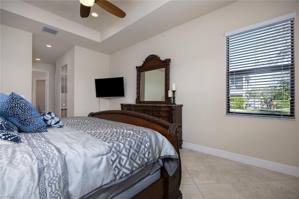 3296 Pacific Drive Naples, FL 34119 - Photo 11 of 50 a bedroom with a large bed and a flat tv screen on dresser