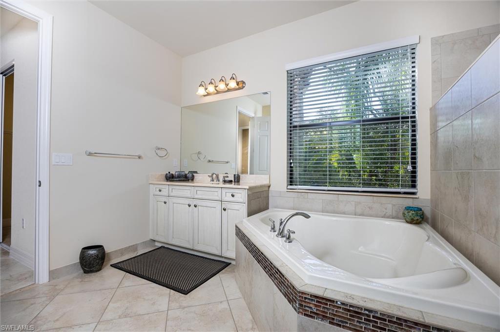3296 Pacific Drive Naples, FL 34119 - Photo 14 of 50 a bathroom with a tub sink and a window