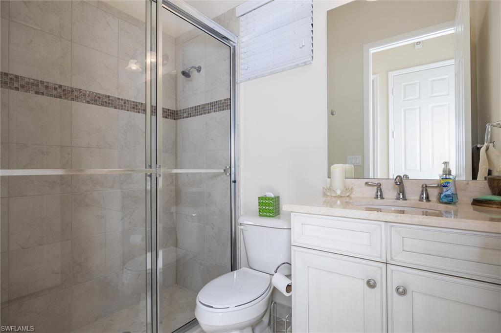 3296 Pacific Drive Naples, FL 34119 - Photo 23 of 50 a bathroom with a granite countertop sink toilet a shower and a mirror
