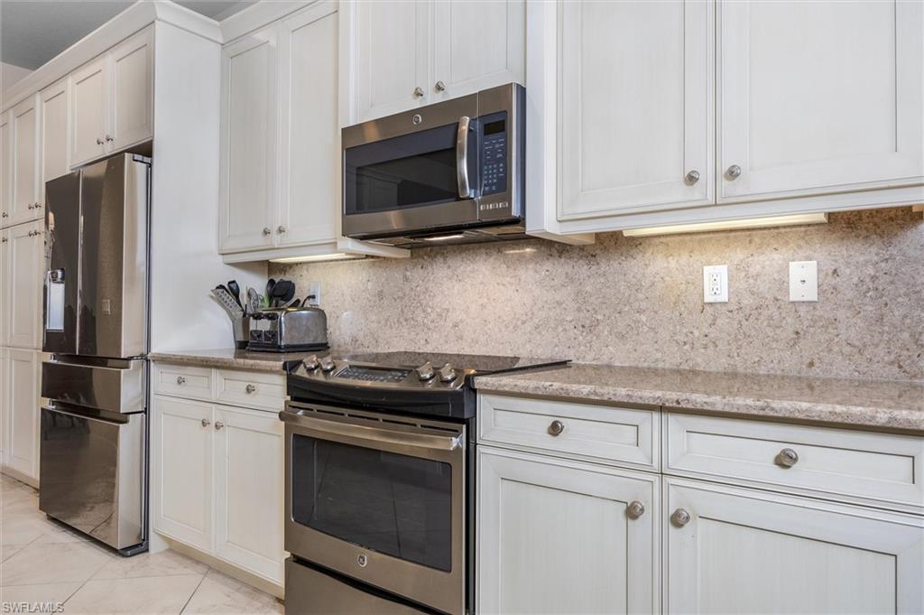 3296 Pacific Drive Naples, FL 34119 - Photo 3 of 50 a kitchen with stainless steel appliances granite countertop white cabinets stove and microwave