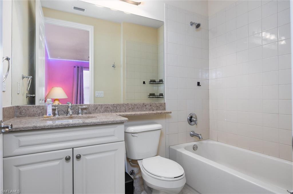 3296 Pacific Drive Naples, FL 34119 - Photo 32 of 50 a bathroom with a granite countertop toilet a sink and a bathtub