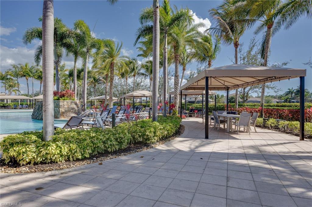 3296 Pacific Drive Naples, FL 34119 - Photo 42 of 50 a view of a patio with a table and chairs under an umbrella with a small garden