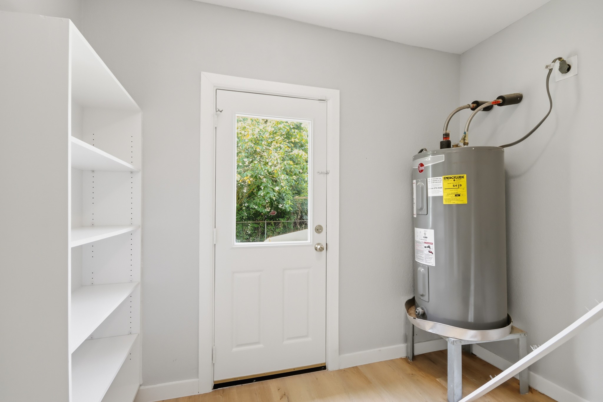 10430 Wiggins Street Houston, TX 77029 - Photo 25 of 27 This utility room features a water heater, shelving, and a door leading outside. Serves for pantry and laundry room