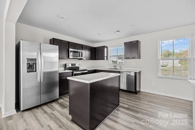 a kitchen with stainless steel appliances granite countertop a refrigerator a stove a sink and a microwave