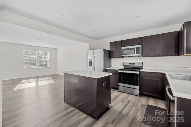 a kitchen with stainless steel appliances a stove refrigerator and a microwave