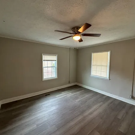 a view of an empty room with window and wooden floor