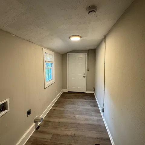 a view of a hallway with wooden floor and a bathroom
