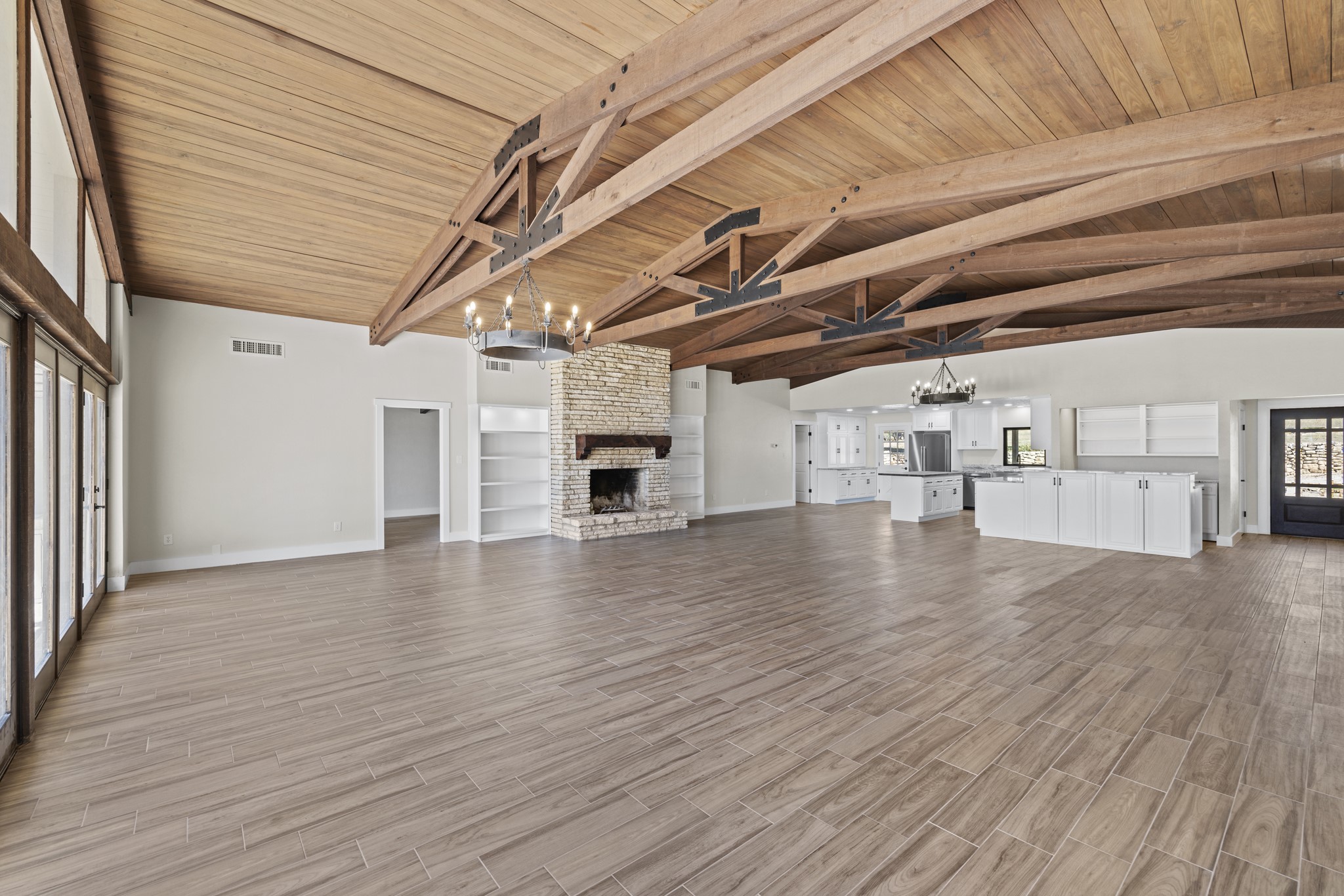 241 Highway 87 Comfort, TX 78013 - Photo 13 of 39 Unfurnished living room featuring a chandelier, a brick fireplace, a wooden ceiling with exposed beams, light wood-type flooring, and high vaulted ceiling